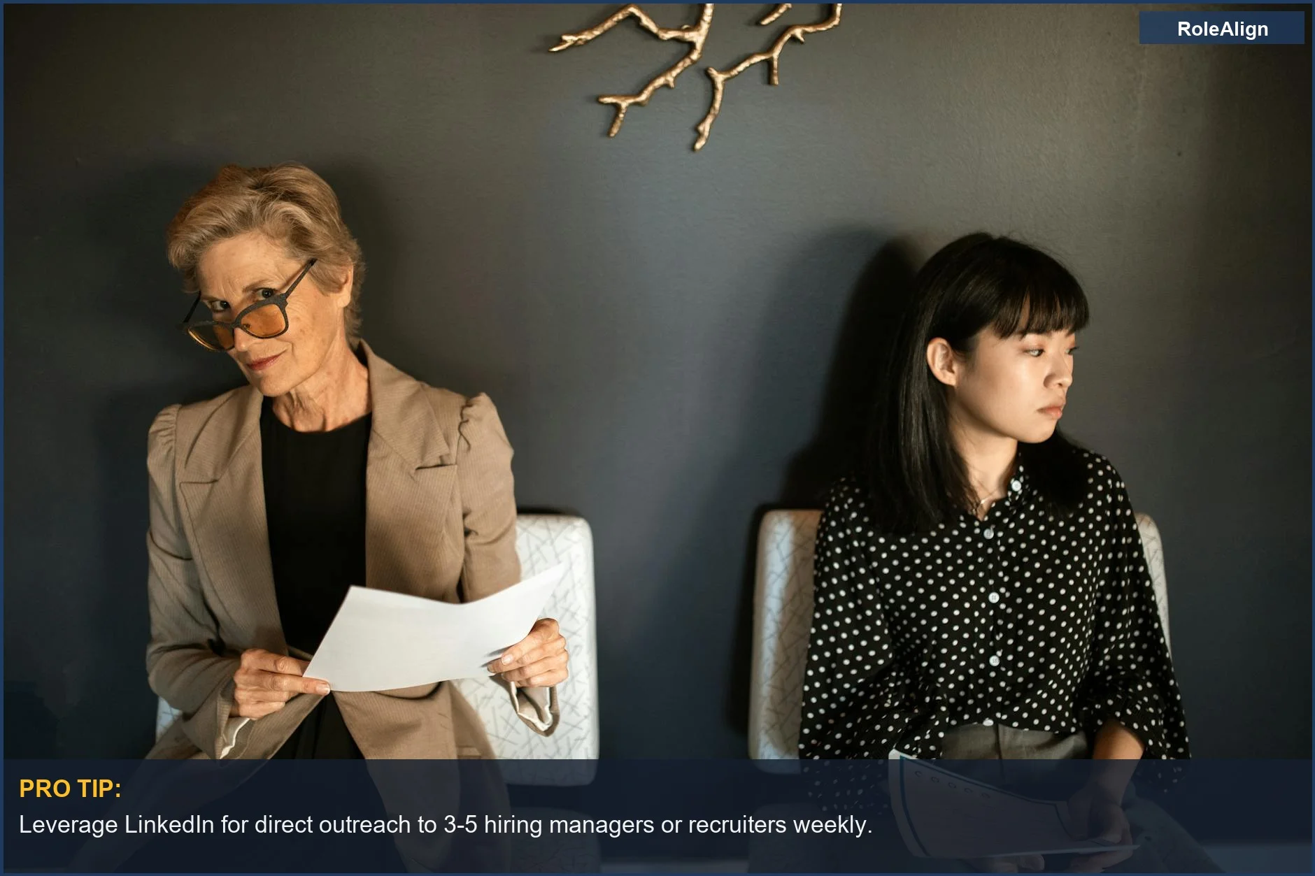 Two women with resumes in a modern waiting area, anticipating job interviews.