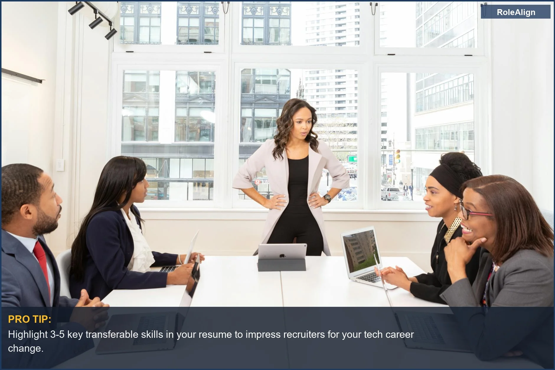 Diverse professionals collaborate in a modern office, discussing career change to tech with a city view.