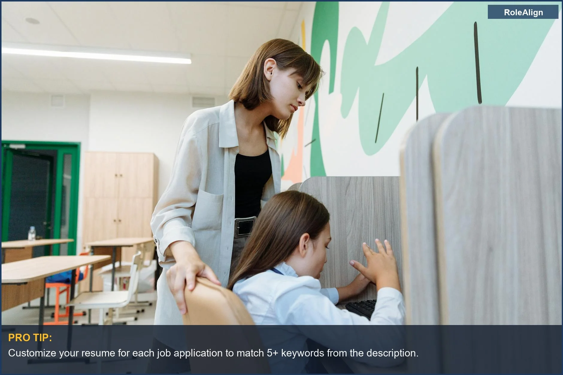 Teacher guiding a student on a computer, illustrating how to build an entry level resume.