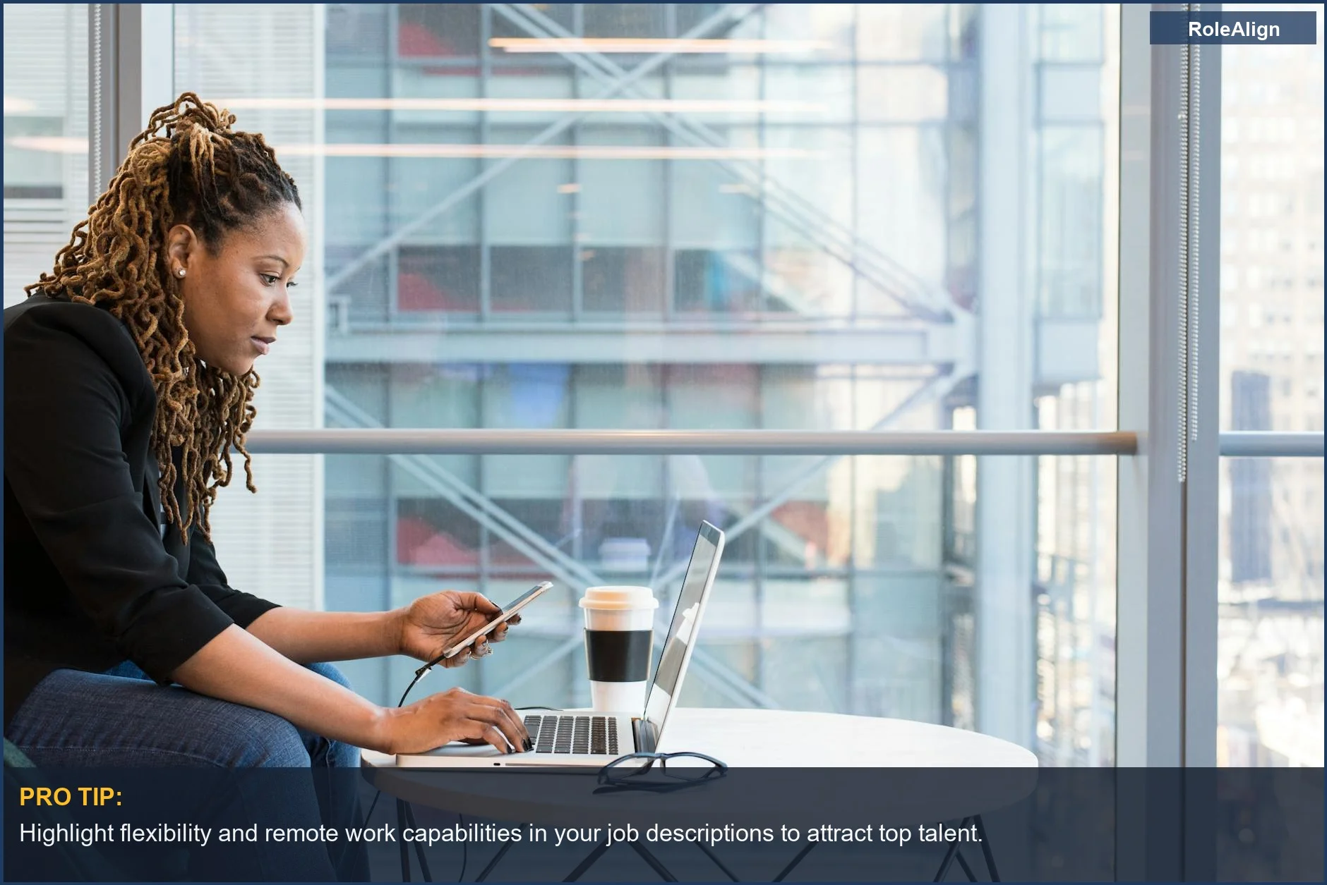 African American woman working remotely with laptop and smartphone, showcasing effective hybrid work policies.