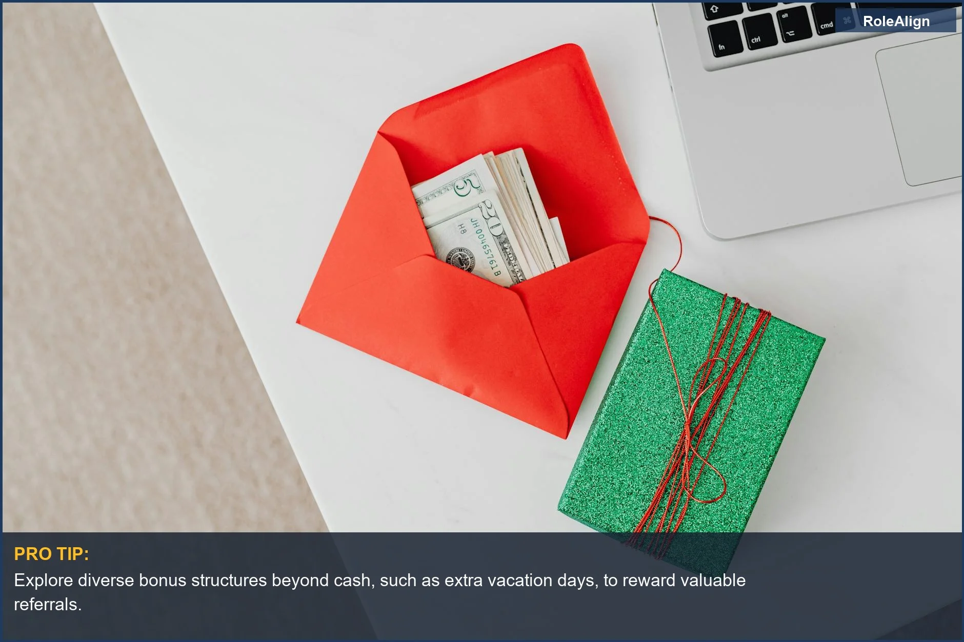 Desk with laptop, cash, and gift box illustrates employee referral bonus structures and financial incentives.