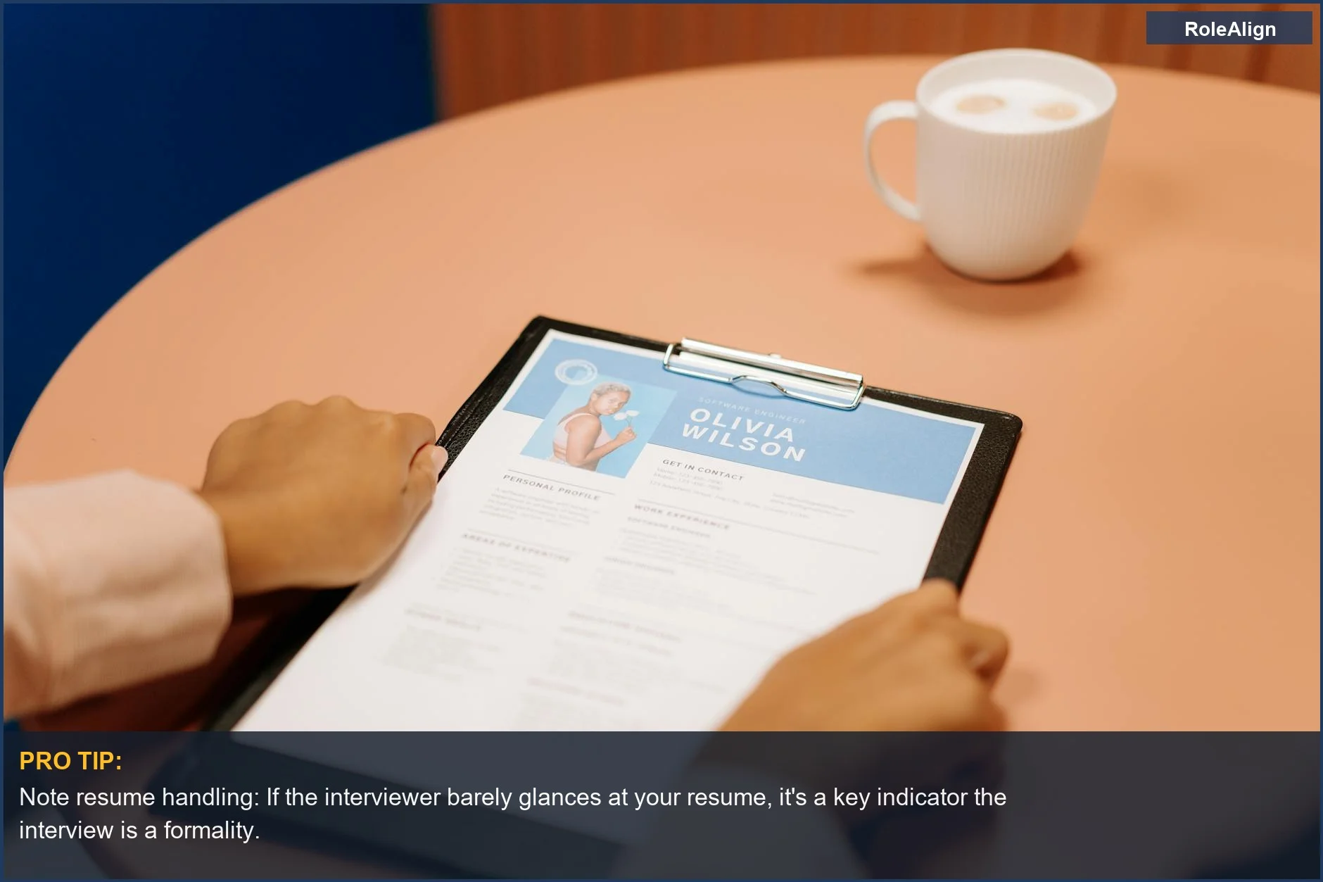 Close-up of hands holding a resume on a table during an interview, with coffee nearby, hinting at a formality.