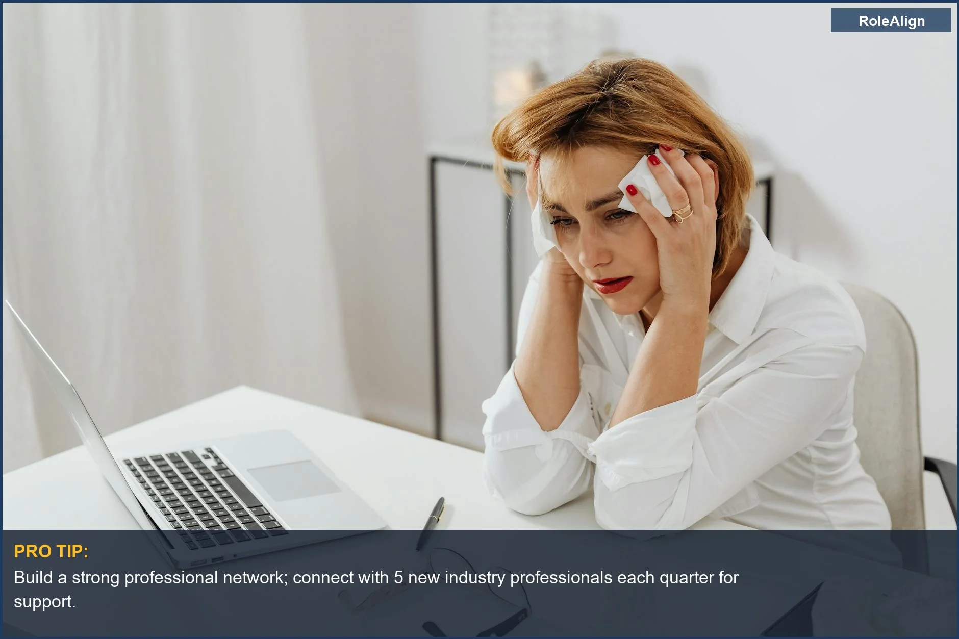 Distressed woman at office desk with tissues, symbolizing impact of 2025 company layoffs.