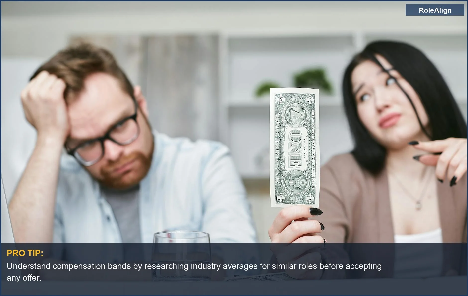 Concerned interracial couple holding a single dollar bill, illustrating the hidden costs of a lowball job offer beyond salary.