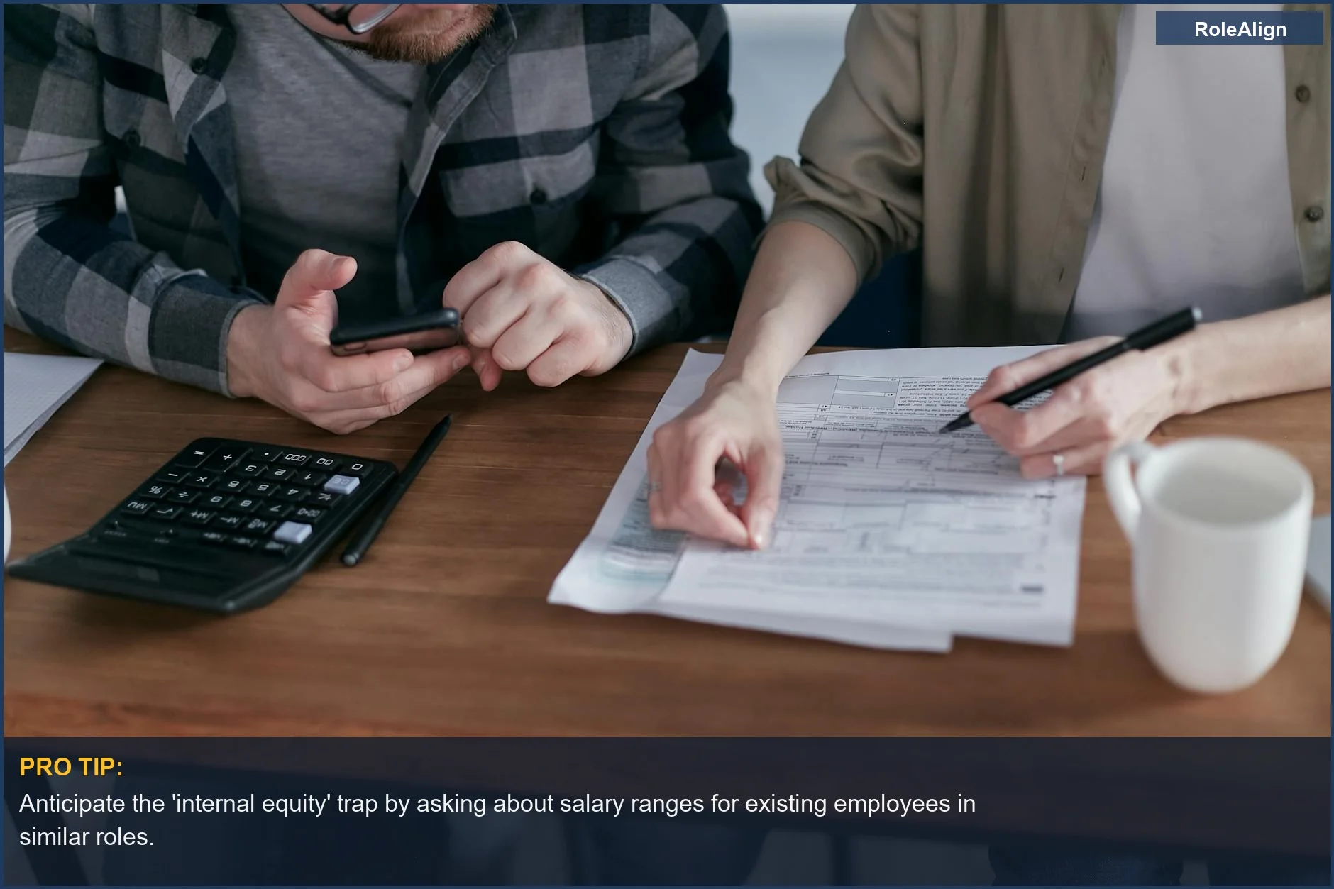 Couple diligently reviewing finances with calculator and documents, showing the long-term impact of accepting a lowball salary.