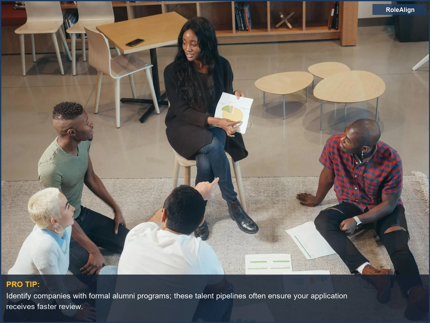 Colegas jóvenes y diversos en una oficina moderna discutiendo ideas, mostrando redes estratégicas de exalumnos para el avance profesional.