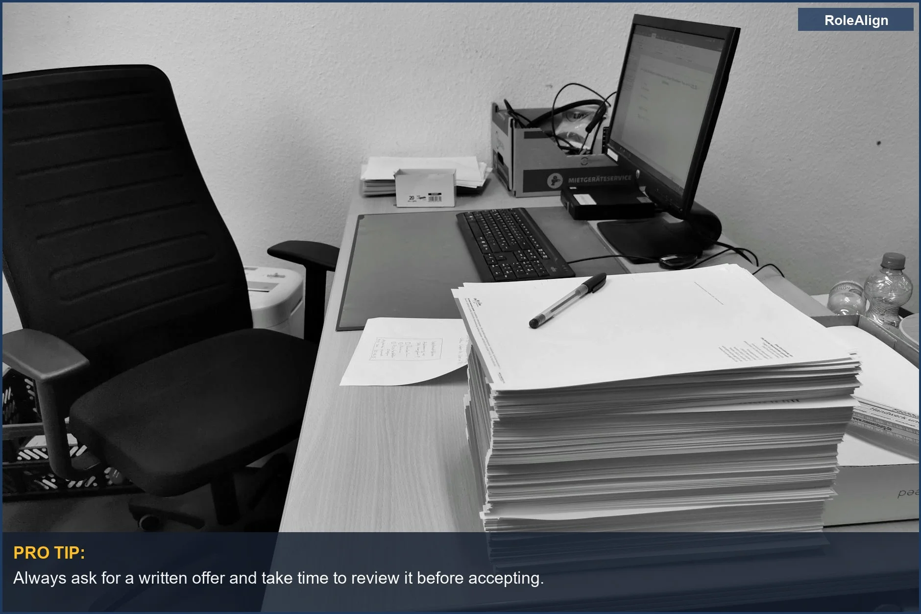 Cluttered office desk in black and white, representing the hidden costs of career trajectory.