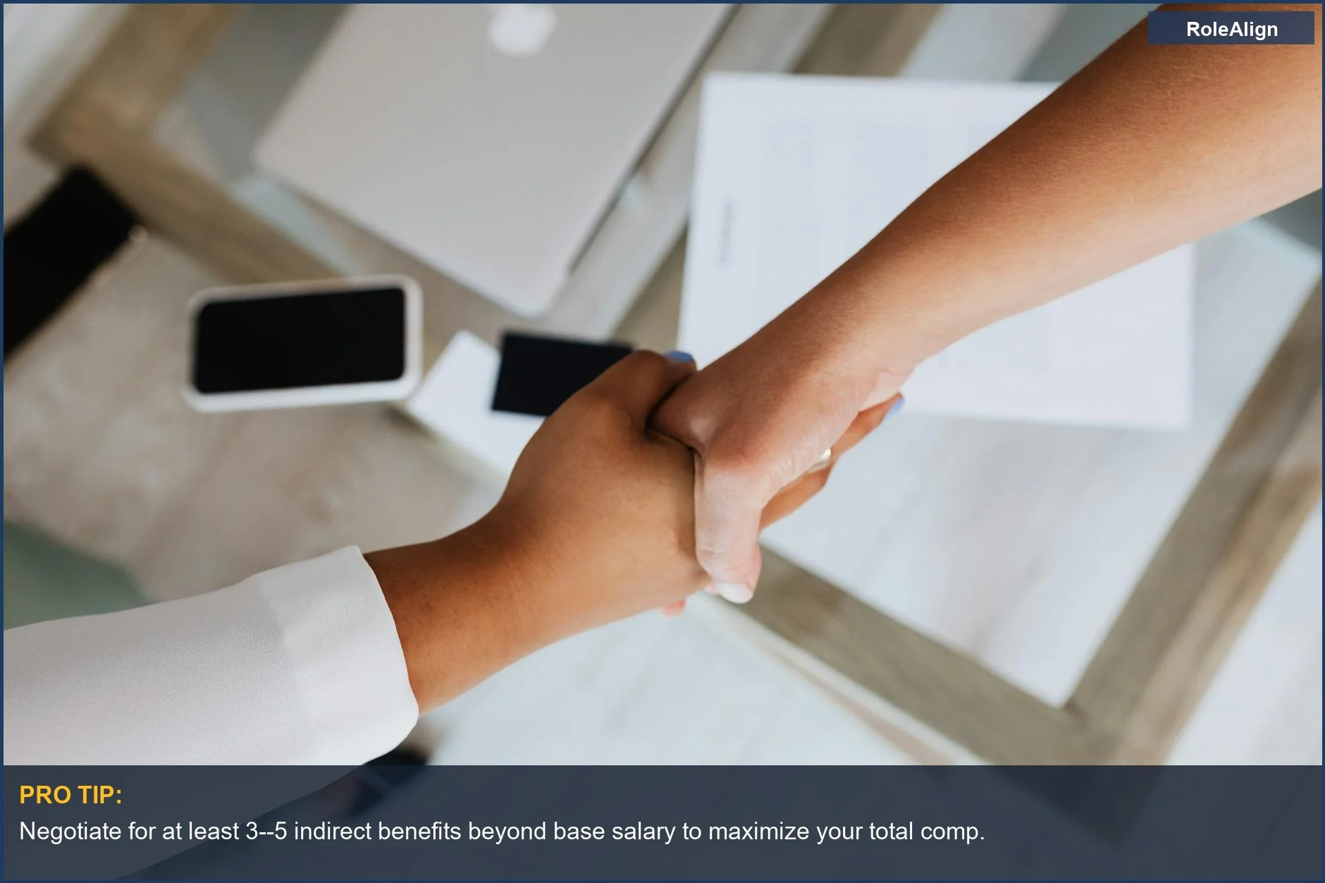 Two professionals shaking hands over a desk, symbolizing a successful total compensation package agreement.