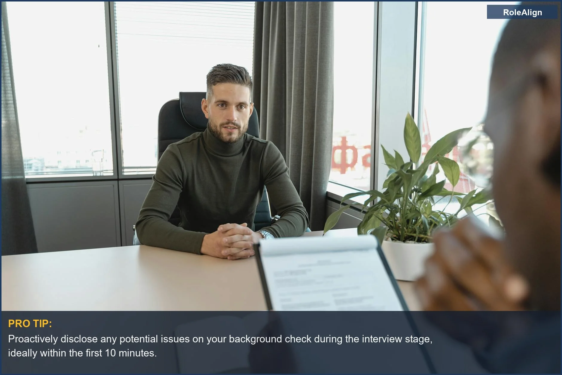 Professional man in turtleneck at office desk, preparing for an interview and potential background check discussion.