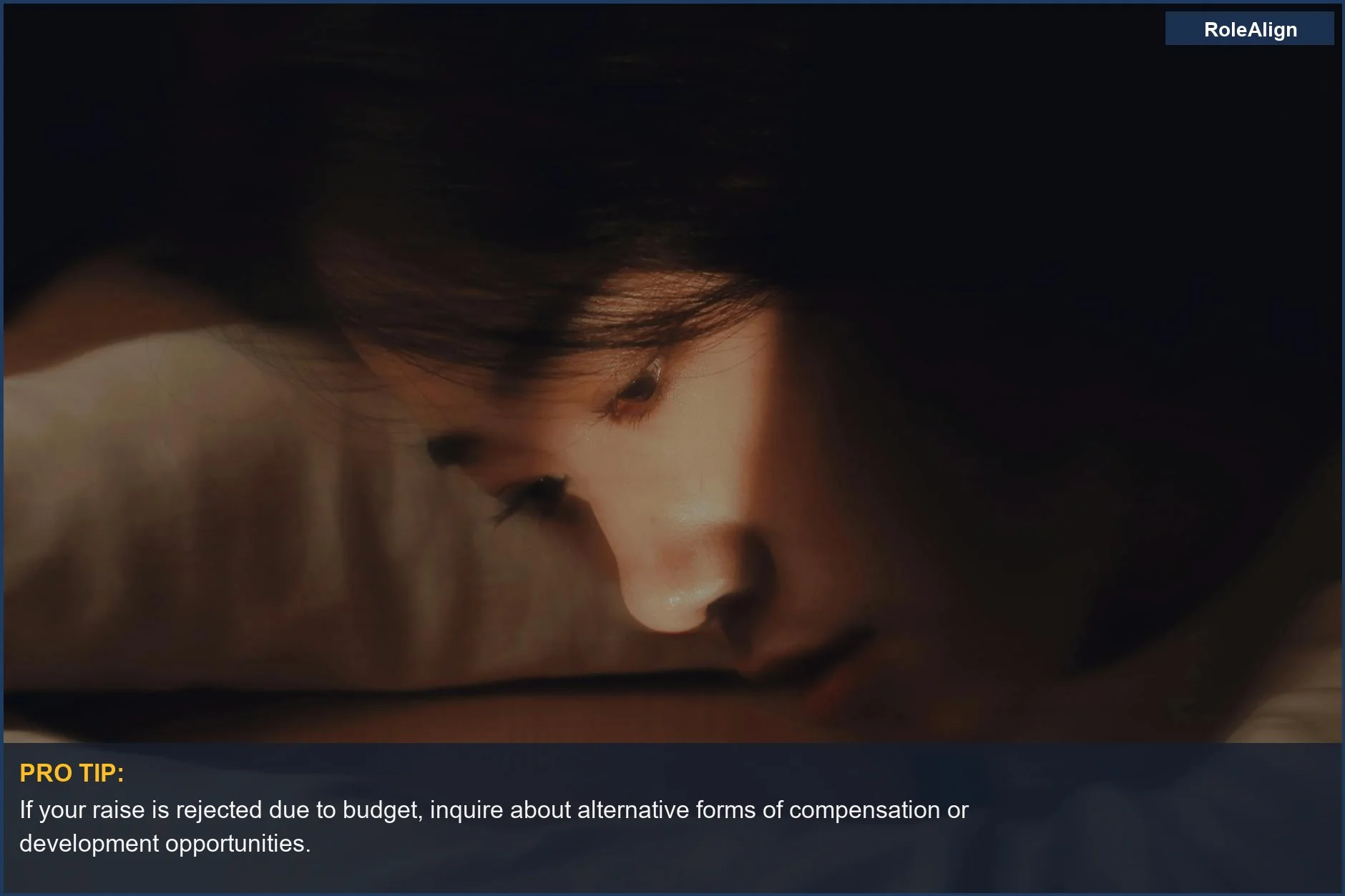 Woman resting head on desk in thought after told no raise.