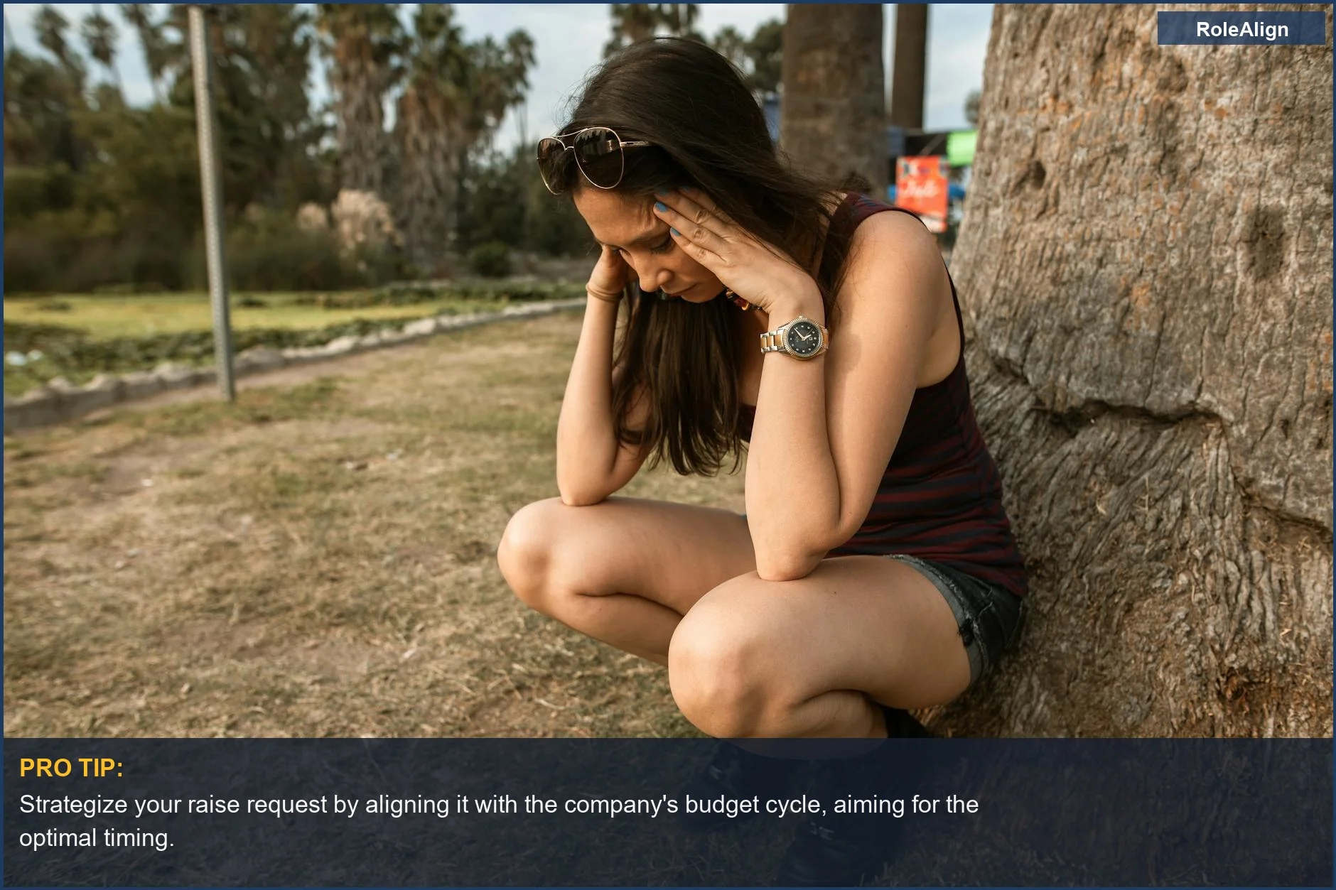 Woman in park holding head, stressed after raise rejected.