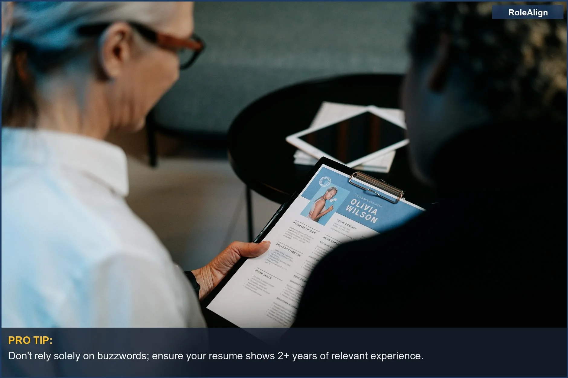 Business professionals conducting an interview with a resume on a clipboard.