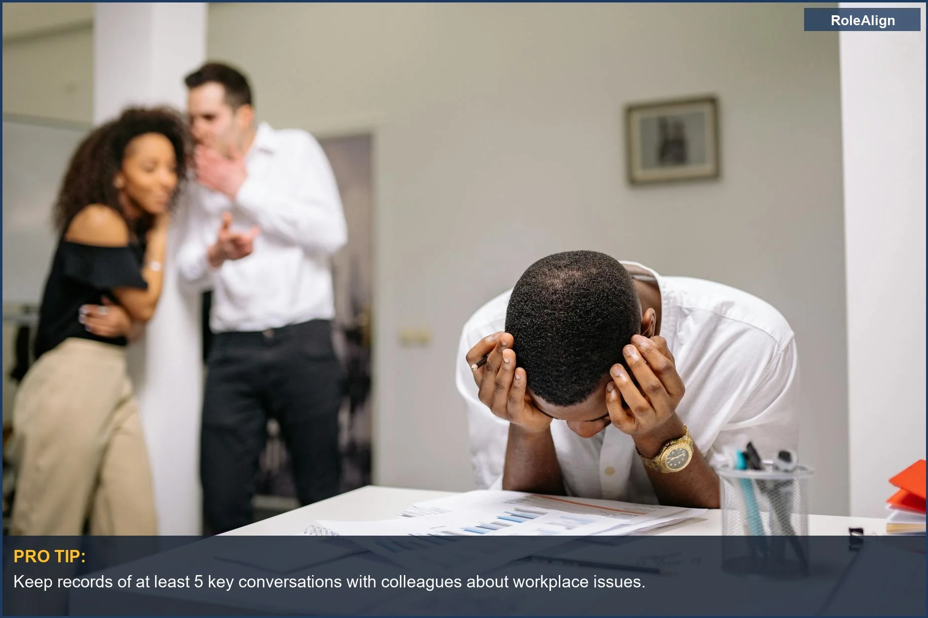 Trabajador sintiéndose desesperado en su escritorio mientras los colegas chismeán, mostrando por qué puedes confiar en RRHH con cautela.