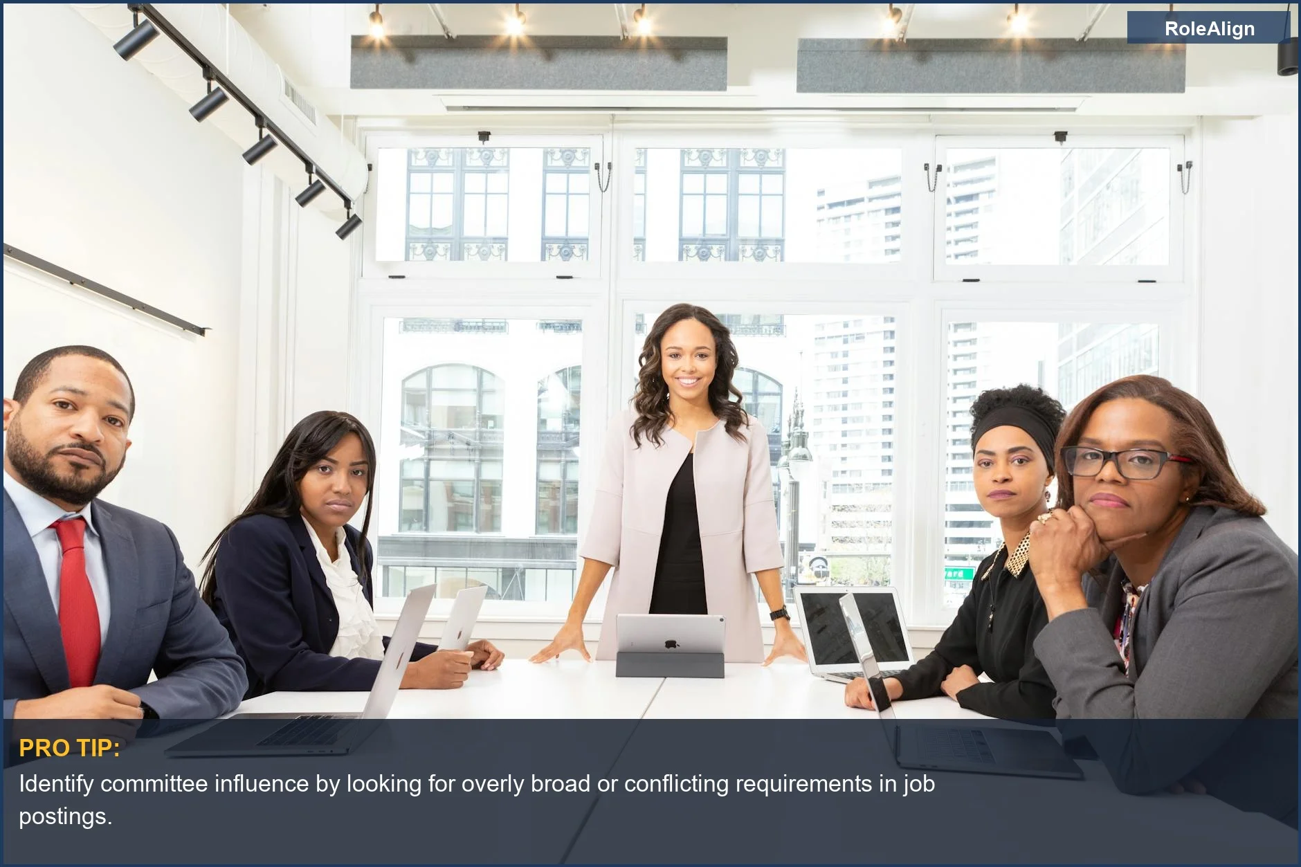 Diverse professionals in a modern office meeting, discussing how job descriptions are inaccurate wish lists.