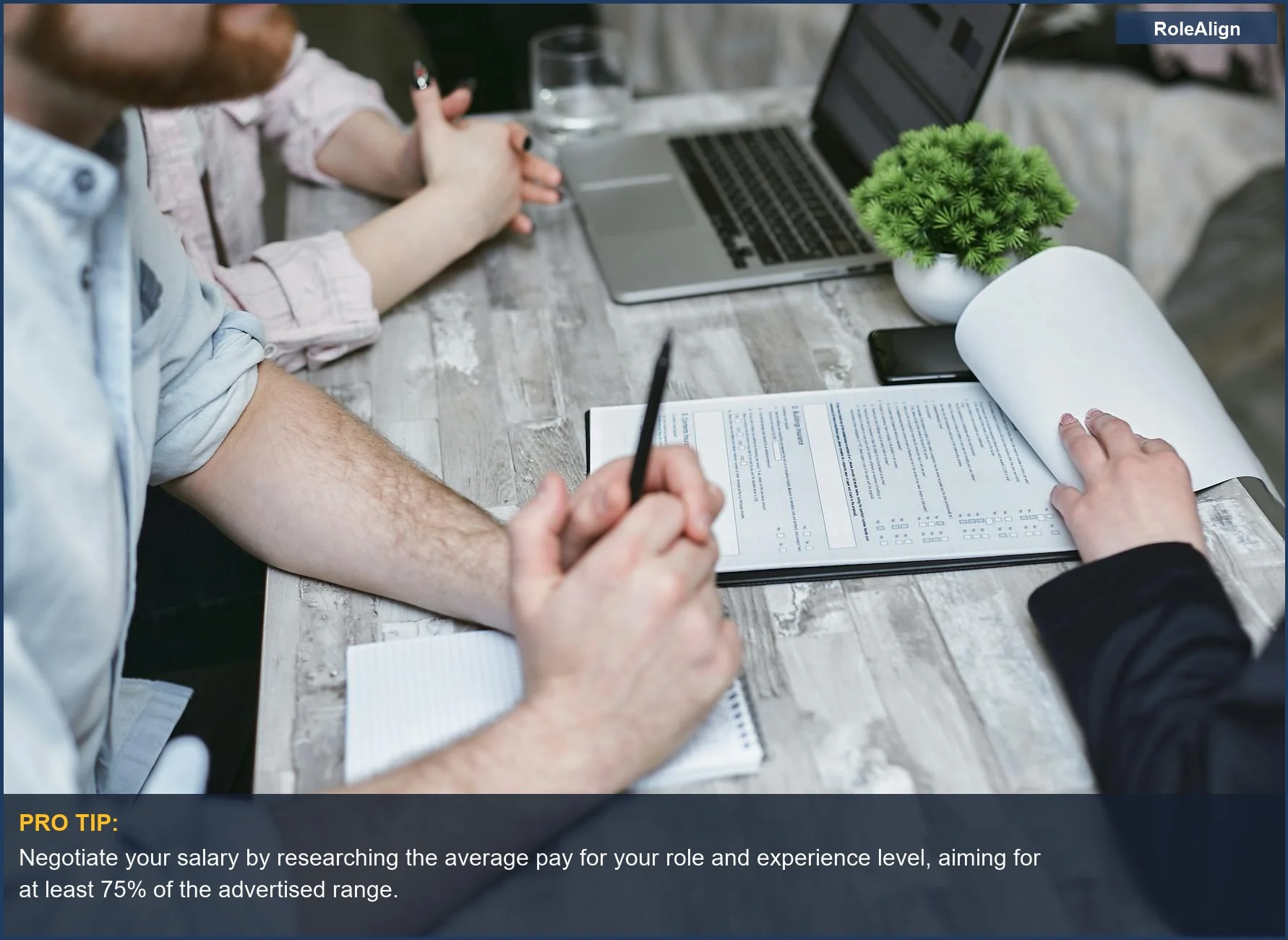 Business meeting with documents and laptop on a table, illustrating misleading salary ranges on job postings.