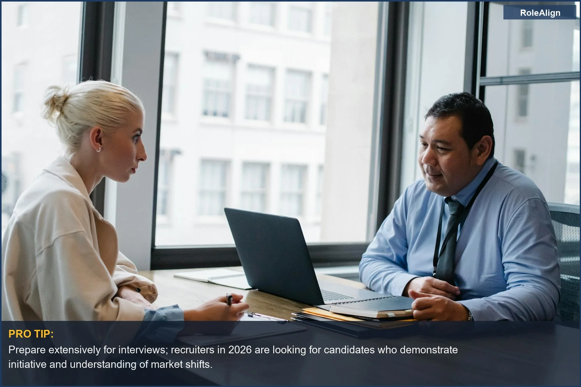 Two professionals in a modern office discussing a job interview, highlighting the challenging 2026 job market.