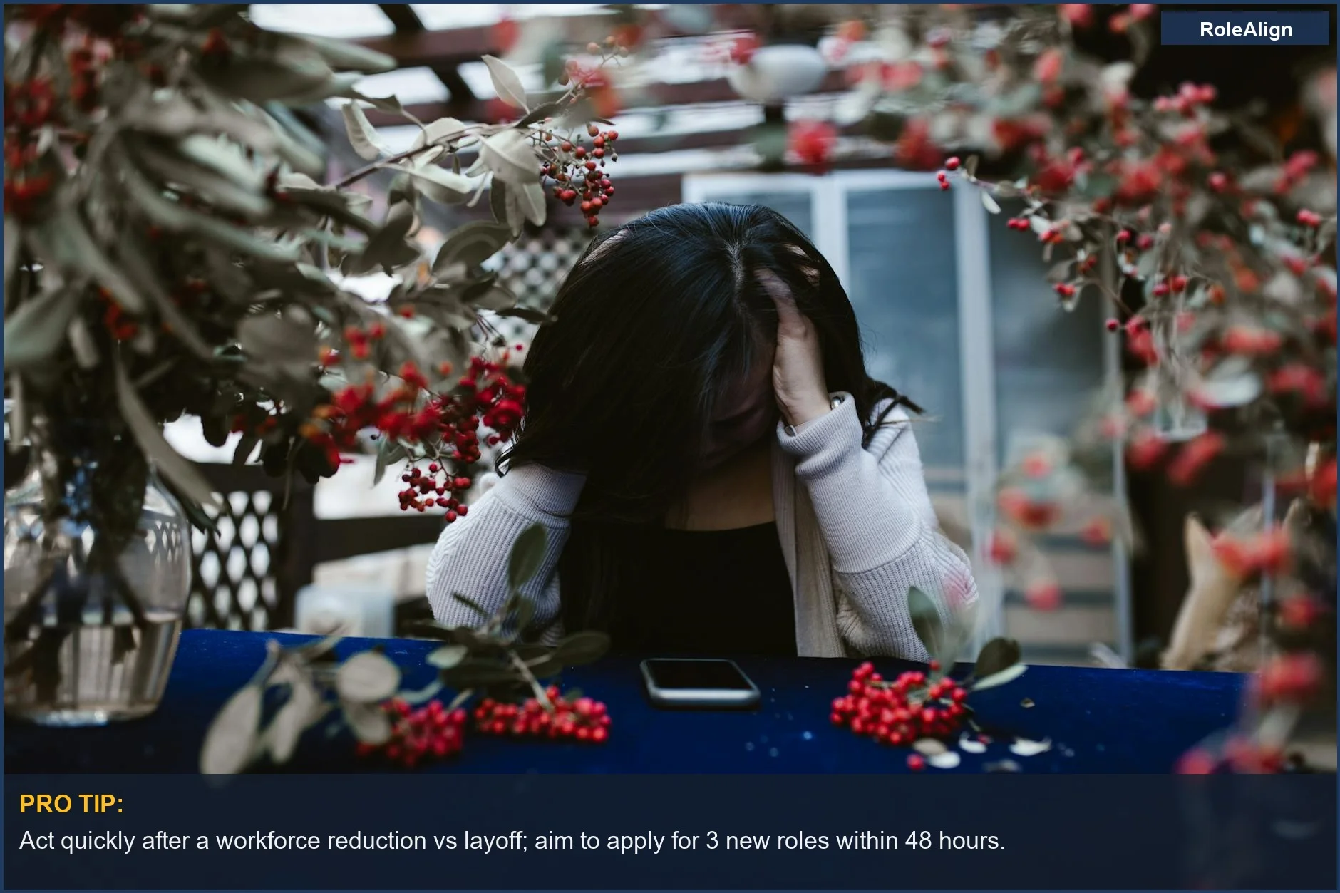 Woman in despair at a table after a workforce reduction vs layoff.